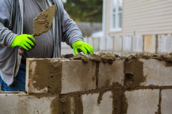 Builder erects a wall erection of blocks