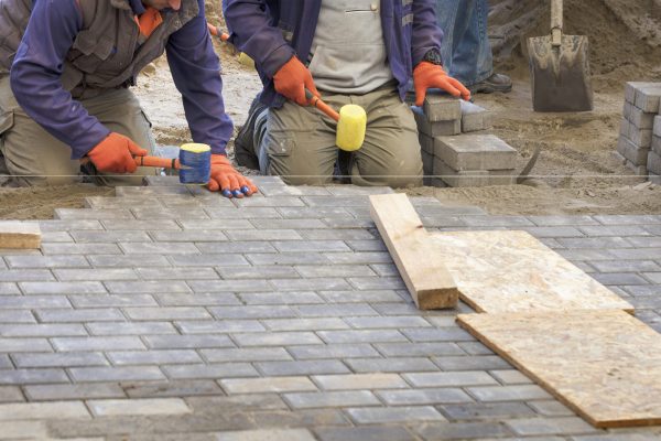 A closeup shot of construction workers laying the paving slab with hammers